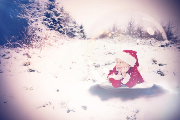 Foto feestelijk kind in sneeuwbol tegen besneeuwd landschap