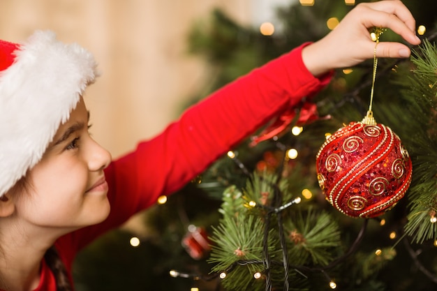 Feestelijk meisje die een Kerstmisdecoratie thuis in de woonkamer hangen