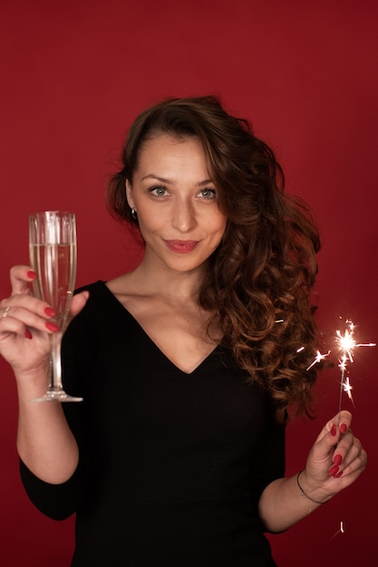 Feestelijk portret van charmante sexy jonge vrouw met champagne en sterretje vieren oudejaarsavond, kopieer ruimte, rode achtergrond. Felicitatie met kerstvakantie, bedrijfsfeest, succes