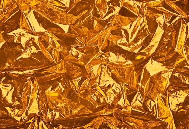 Feestelijke abstracte achtergrond van gouden oranje verfrommeld glanzend metallic plastic folie close-up