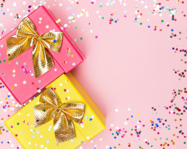 Feestelijke achtergrond met twee kleuren geschenkdozen, gouden strikken en sprankelende confetti