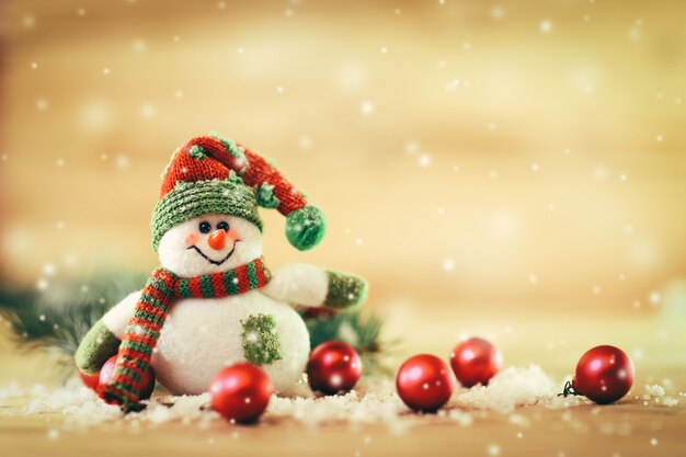 Feestelijke achtergrond. sneeuwpop verkleed als kerstman met kerstballen op een lichte achtergrondfoto heeft een lege ruimte voor uw tekst