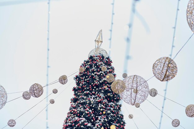 Feestelijke buitenkerstboom met felle lichten en bollen op de winteravond voor de hemel Nieuwjaarsvakantie