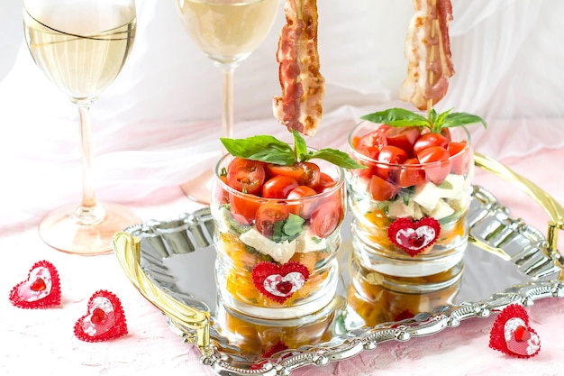 Feestelijke caprese salade met gebakken spek op spiesjes in glazen