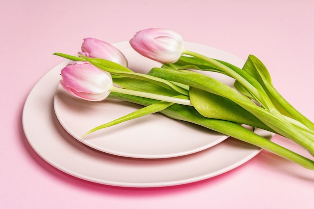 Feestelijke creatieve roze tafel met tulpen op de zachtroze achtergrond