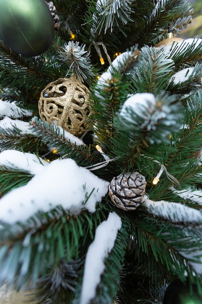 Feestelijke dennenboom met slinger en een gouden bal in close-up.