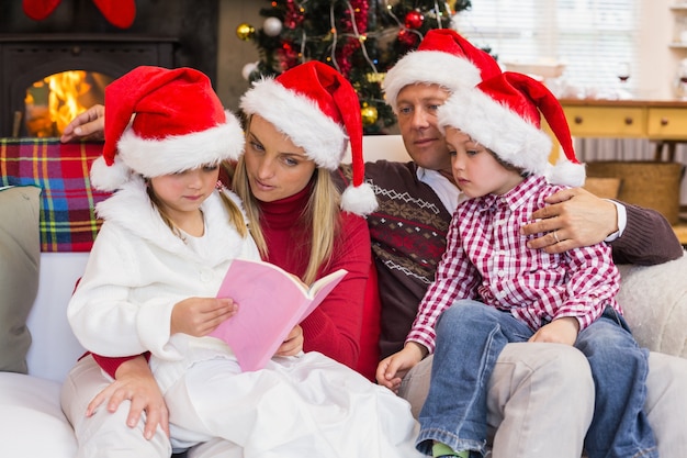 Feestelijke familie die santahoed draagt ​​terwijl het lezen op de laag