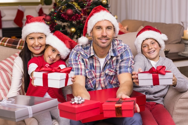 Feestelijke familie op de bank die giften aanbiedt