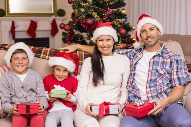 Feestelijke familie poseren met geschenken op de bank