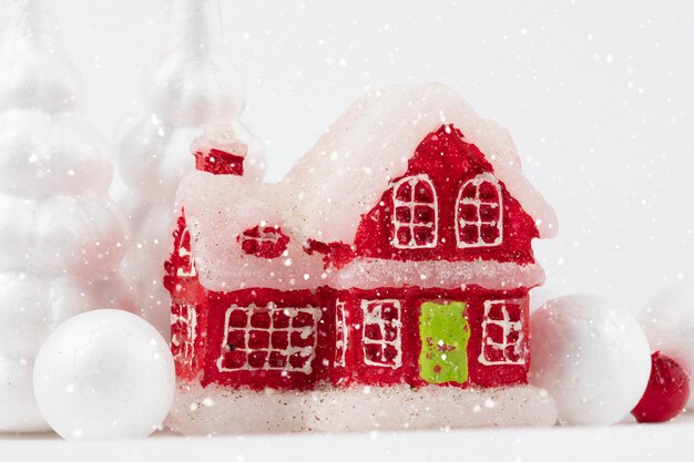 Feestelijke kerstachtergrond Rood besneeuwd miniatuurhuis en zilveren kerstbomen