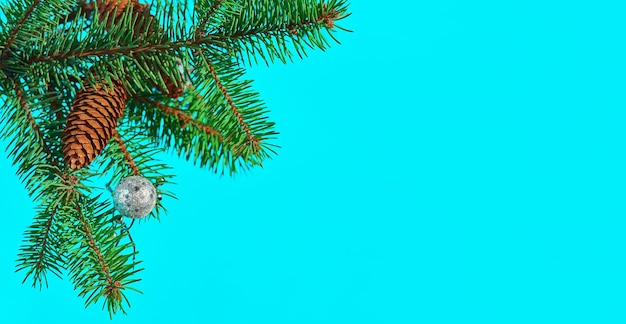 Feestelijke kerstkaart met een fir-tree branch met kegels en speelgoed op een turquoise tafel, selectieve aandacht.