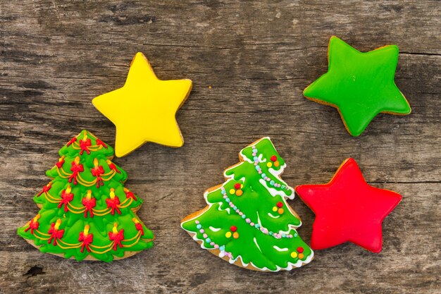 Feestelijke kerstkoekjes in de vorm van een kerstboom en sterren. Lekkere peperkoeken op rustieke houten tafel. Bovenaanzicht