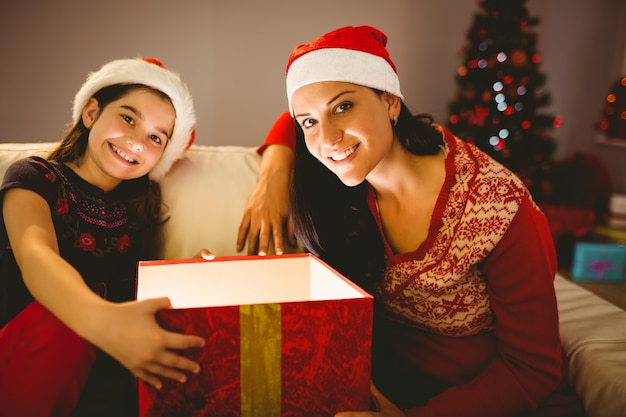 Feestelijke moeder en dochter die een gloeiende Kerstmisgift openen