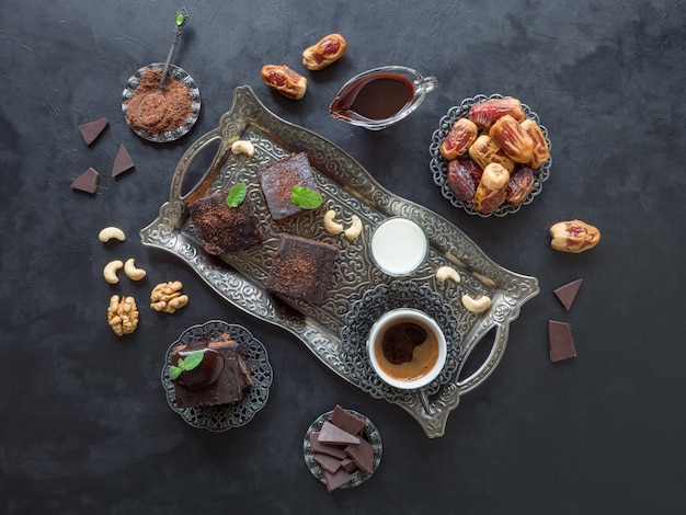 Feestelijke Ramadan. Brownies met dadels, melk en koffie liggen op een zwarte ondergrond.