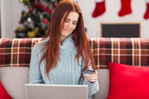 Feestelijke roodharige die laptop op laag met behulp van