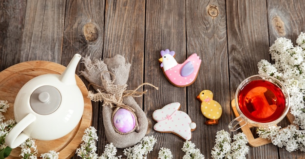 Feestelijke samenstelling van Pasen met paaskoekjes en een kopje thee op houten tafelblad bekijken.