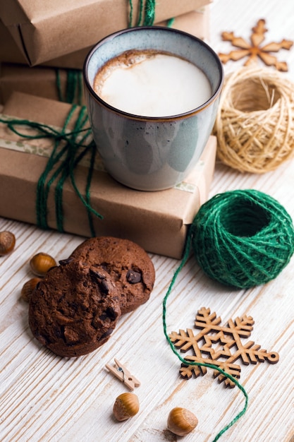Feestelijke stemming. Geschenken, kopje cappuccino en kerst decor op de houten achtergrond.