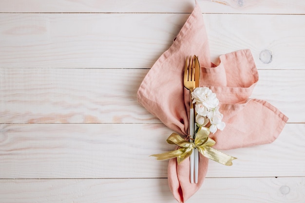 Feestelijke tafel Bestek met roze servet en geschenkdoos op witte houten achtergrond Mooi platliggend arrangement Bovenaanzicht met kopieerruimte