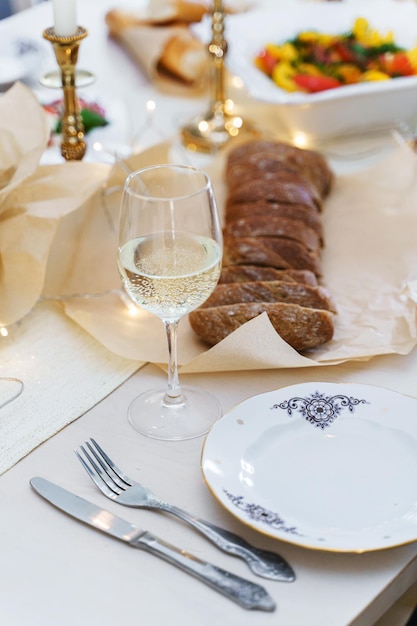 Feestelijke tafel geserveerd voor het diner met gesneden brood en witte wijn versierd met kaarsen