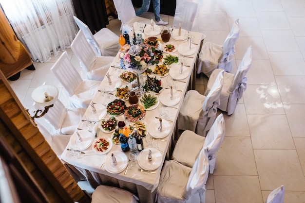 Feestelijke tafel in de feestzaal Gasten bedienen tafel dekken Borden zilverwerk bestek glazen servet Bruiloft tafeldecoratie Bovenaanzicht