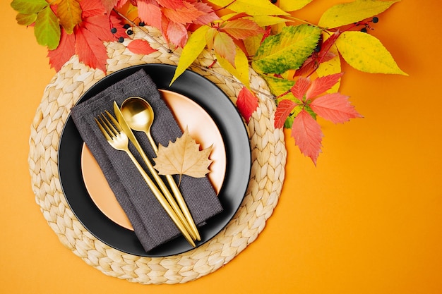 Feestelijke tafel setting met heldere herfstbladeren op oranje achtergrond. platliggend, bovenaanzicht, kopieerruimte