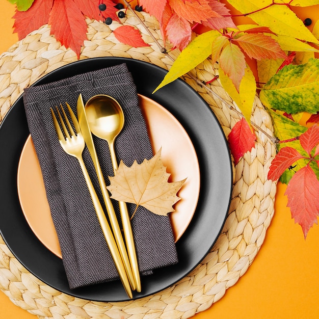 Feestelijke tafel setting met heldere herfstbladeren op pastel achtergrond.