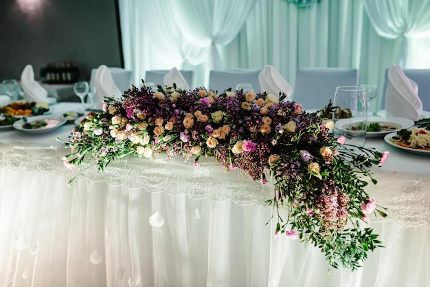 Feestelijke tafel versierd met compositie van roze bloemen en groen in de feestzaal Tafel pasgetrouwden in de feestzaal op huwelijksfeest