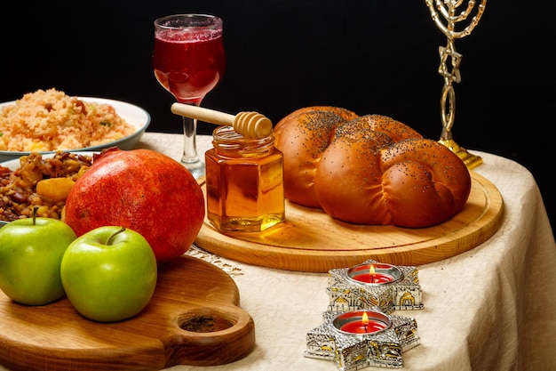 Feestelijke tafel voor een maaltijd op rosj hasjana challah honing granaatappel appels wijn en traditionele chelnt