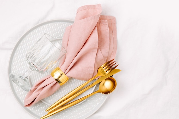 Feestelijke tafelschikking. borden en bestek met roze servet op witte achtergrond. mooi platliggend arrangement.