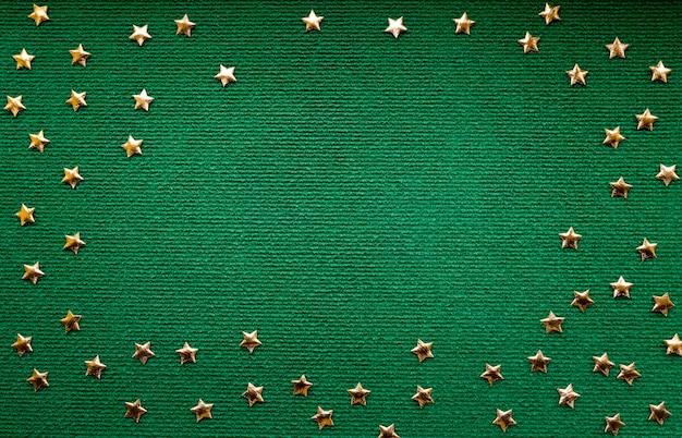 Feestelijke textielachtergrond in groene kleur met heldere gouden sterren bovenaanzicht wol en pailletten Kerstmis