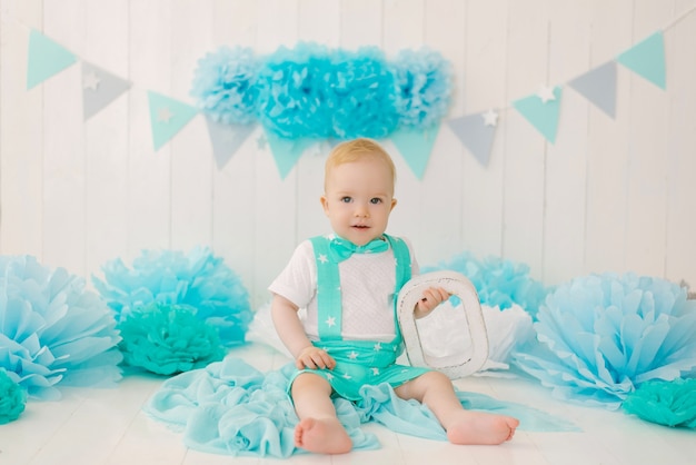 Feestvarken 1-jarige jongen, babysitter met blauwe slingers en de letter O in een pak en vlinderdas