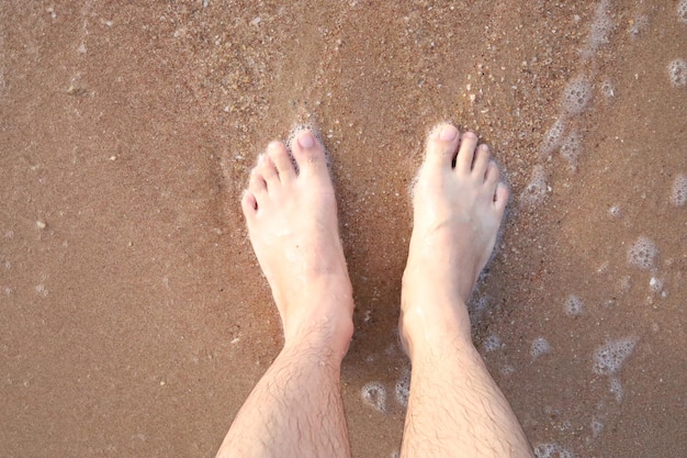 Feet on the beach with sand and ocean waves