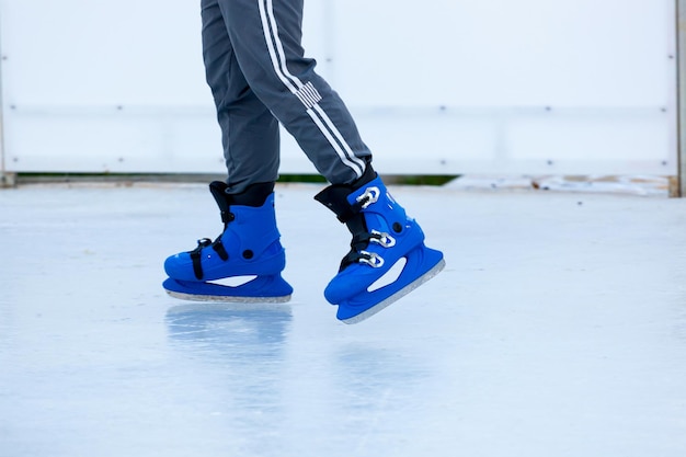 Feet in in blue boots on skates on an open skating rink