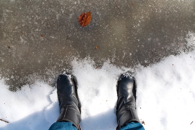 Feet in boots in a frozen puddle