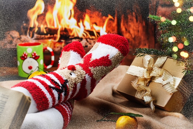 Feet in bright Christmas socks near fireplace