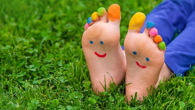 Feet of a child on the grass with a painted smile Selection focus