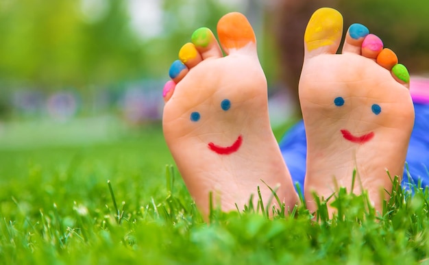 Feet of a child on the grass with a painted smile Selection focus