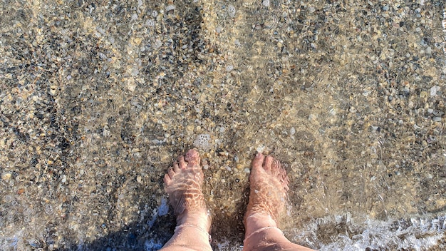 Feet in clear sea water top view