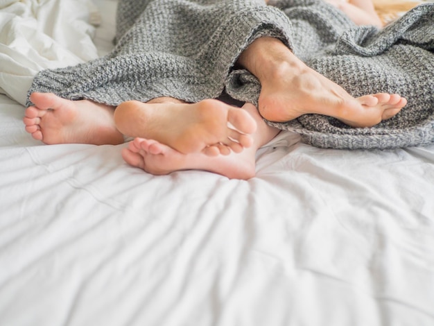 Feet of a couple under blanket close up view love rest and relationship concept