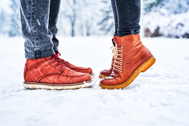 Feet of a couple on a snowy sidewalk in brown boots