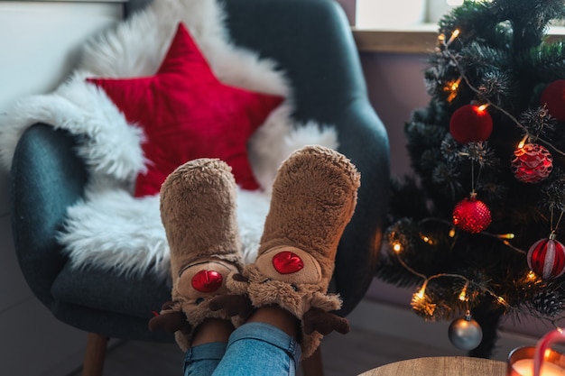 Photo feet in cute slippers on the background of the christmas tree.