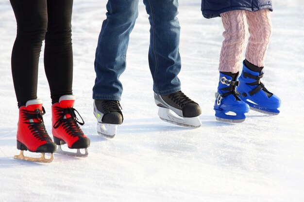 Feet of different people skating on the ice rink
