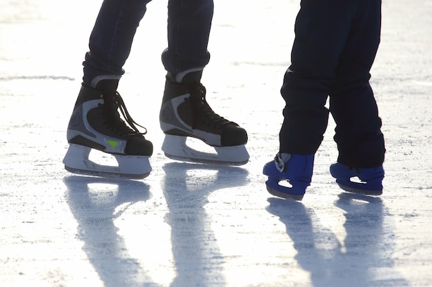 Feet of different people skating on the ice rink