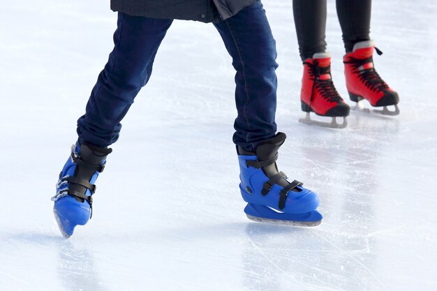 Feet of different people skating on the ice rink
