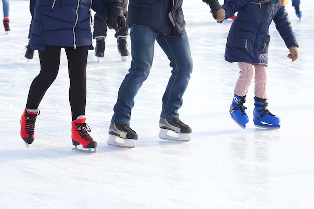 Feet of different people skating on the ice rink
