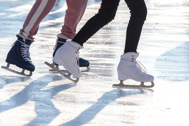 Feet of different people skating on the ice rink