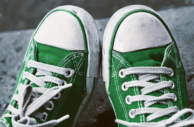 Photo feet in dirty green sneakers and jeans outdoors