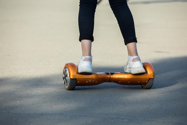 Feet of girl riding on electric mini gyro scooter board in parkxA