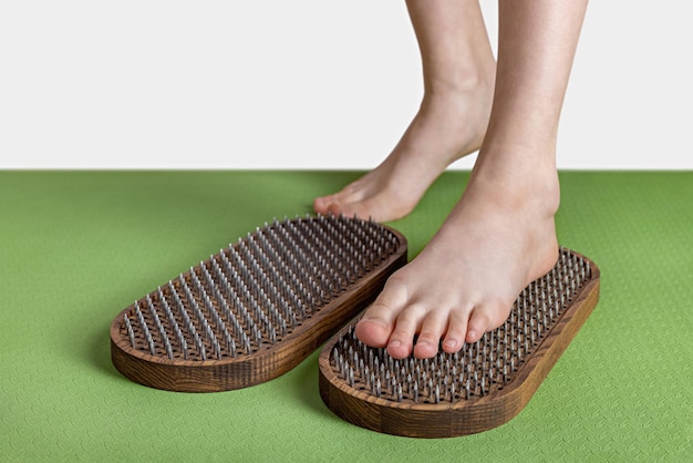 Feet of a girl stepping on a wooden sadhu yoga board Workouts at home and in the club