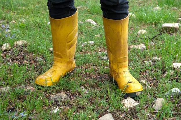 写真 雨の時の草の上で黄色いブーツを履いた足